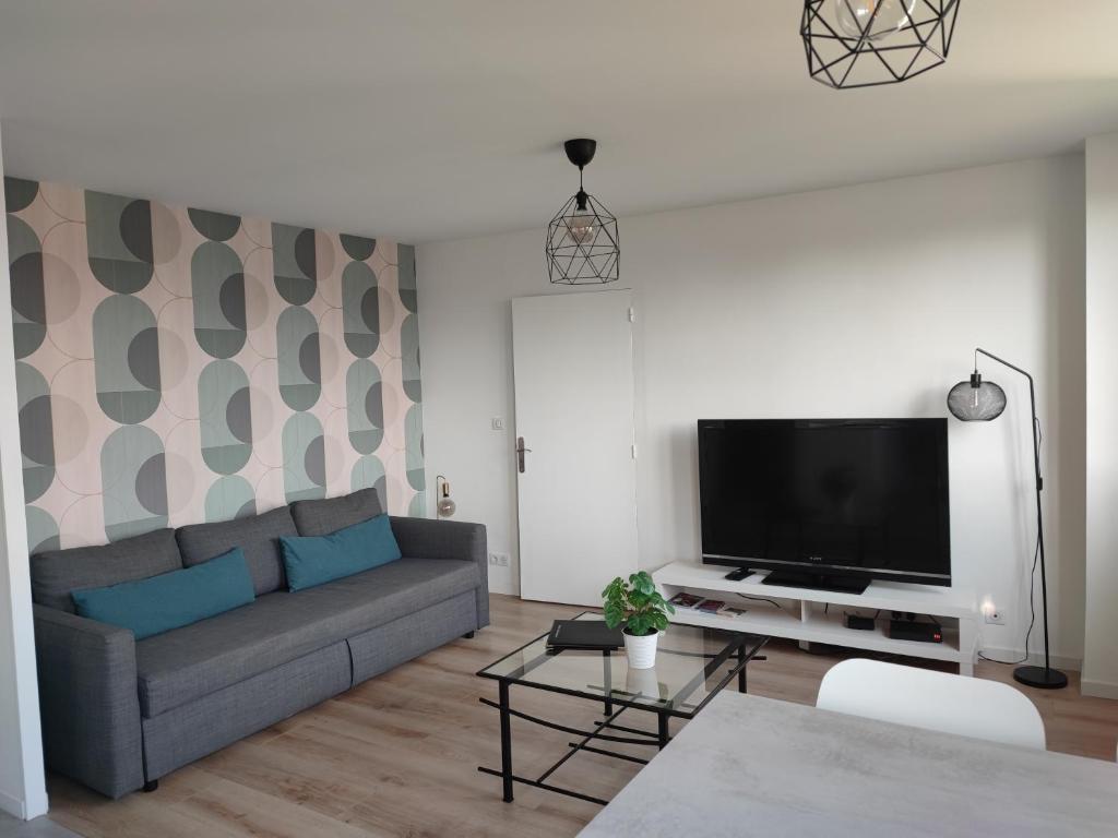 een woonkamer met een bank en een flatscreen-tv bij Arandes in Dijon