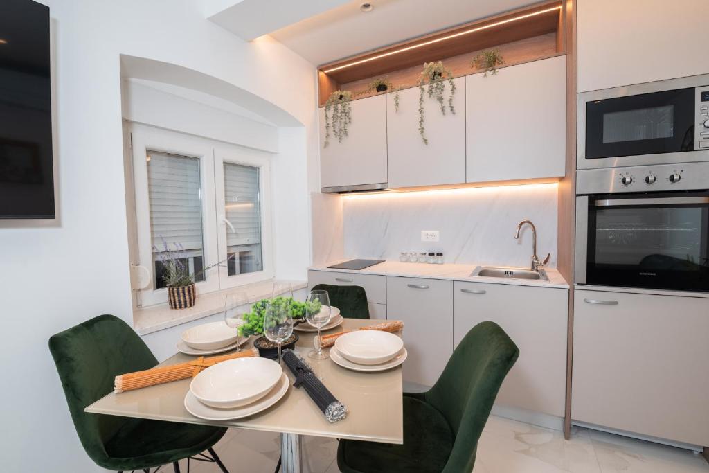 a kitchen with a table and chairs and a kitchen with white cabinets at Canta Amore II in Zadar