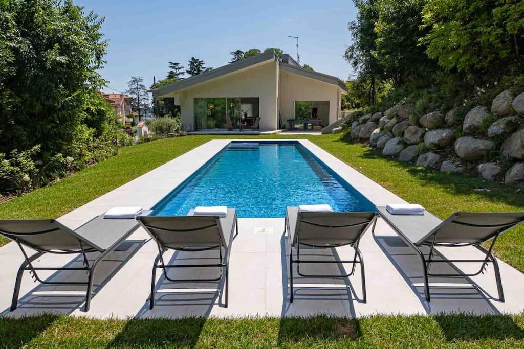 a swimming pool with chairs next to a house at Villa Prince Garda in Salò