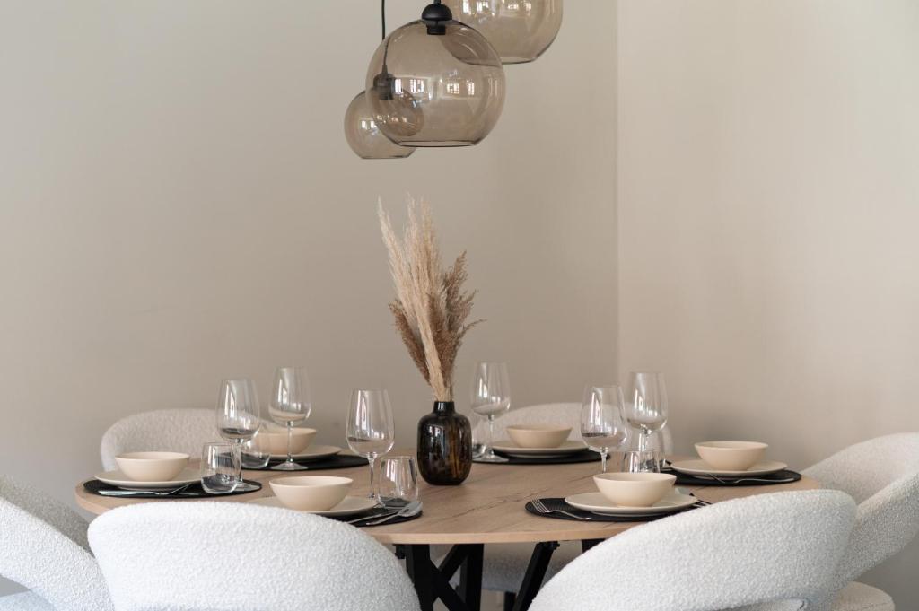 a dining room table with white chairs and a table with glasses at Gastenkamers Ten Huyze Marchandise in Bruges