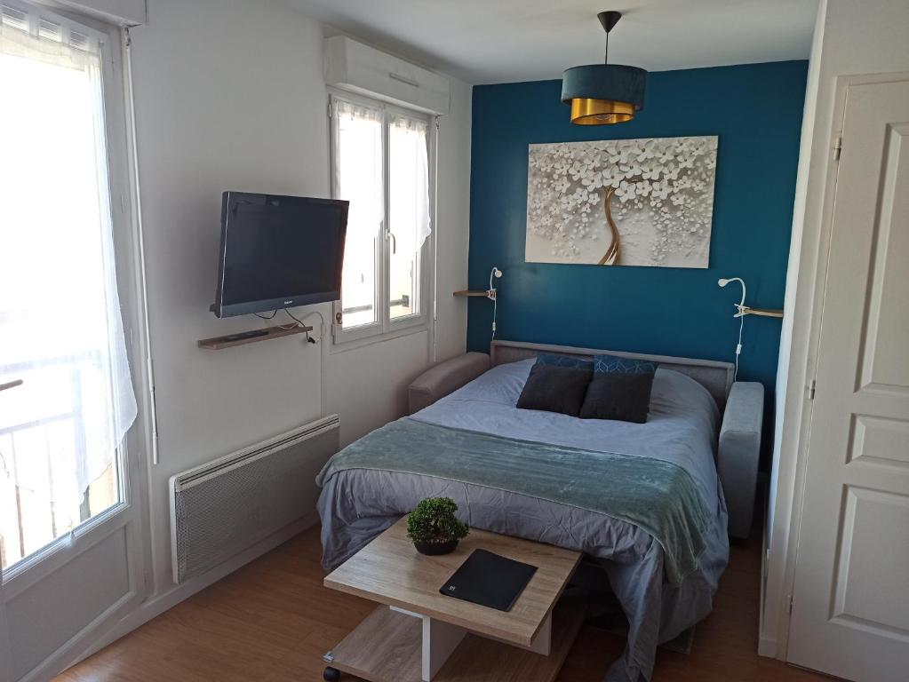 een slaapkamer met een bed en een tv aan de muur bij Studio cosy, Meaux centre, Disney-Paris, proche gare et activités in Meaux