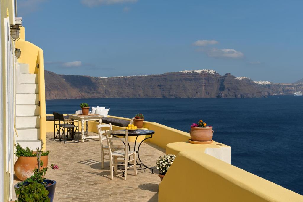 a balcony with tables and chairs overlooking the ocean at Ilivatos in Oia