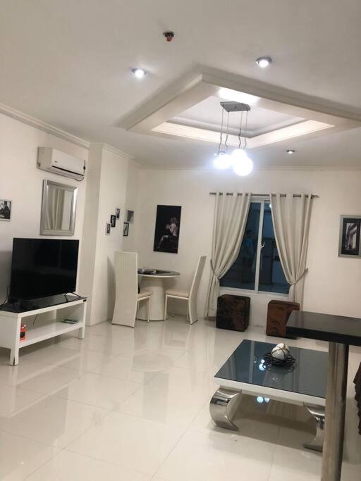 a living room with a television and a table in it at Sheryll Escapes - Kandi comfortable 1bedroom, king bed, housekeeping in Angeles