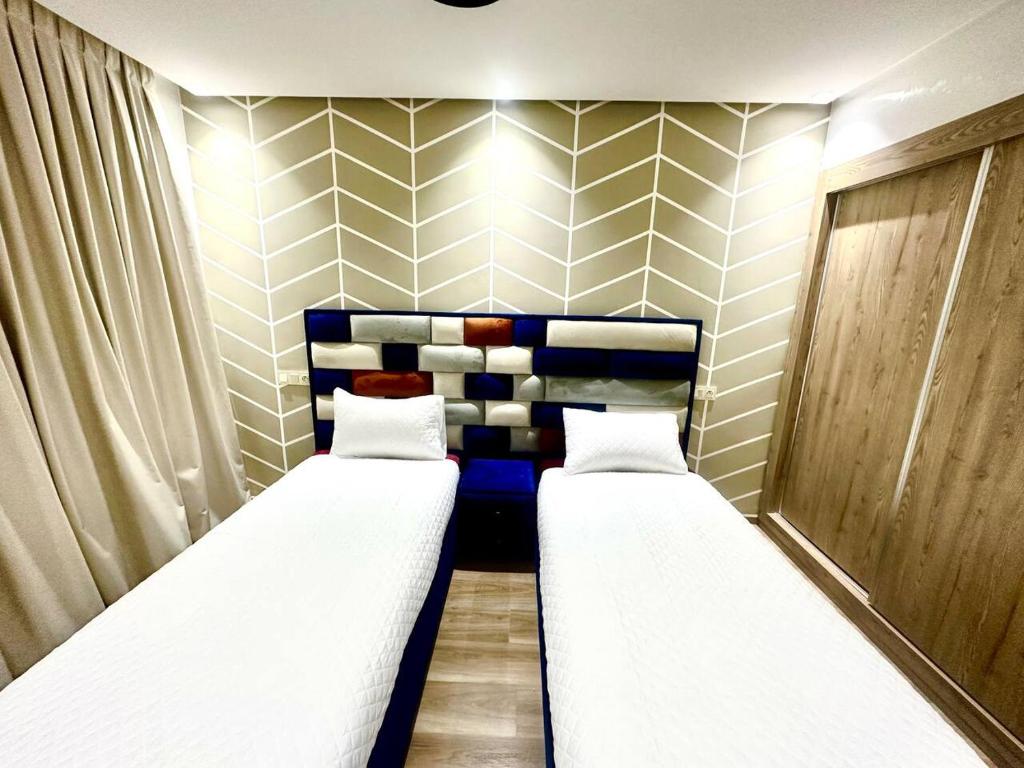 2 camas en una habitación pequeña con paredes a rayas en Appartement Cozy avec piscine, en Sidi Rahal