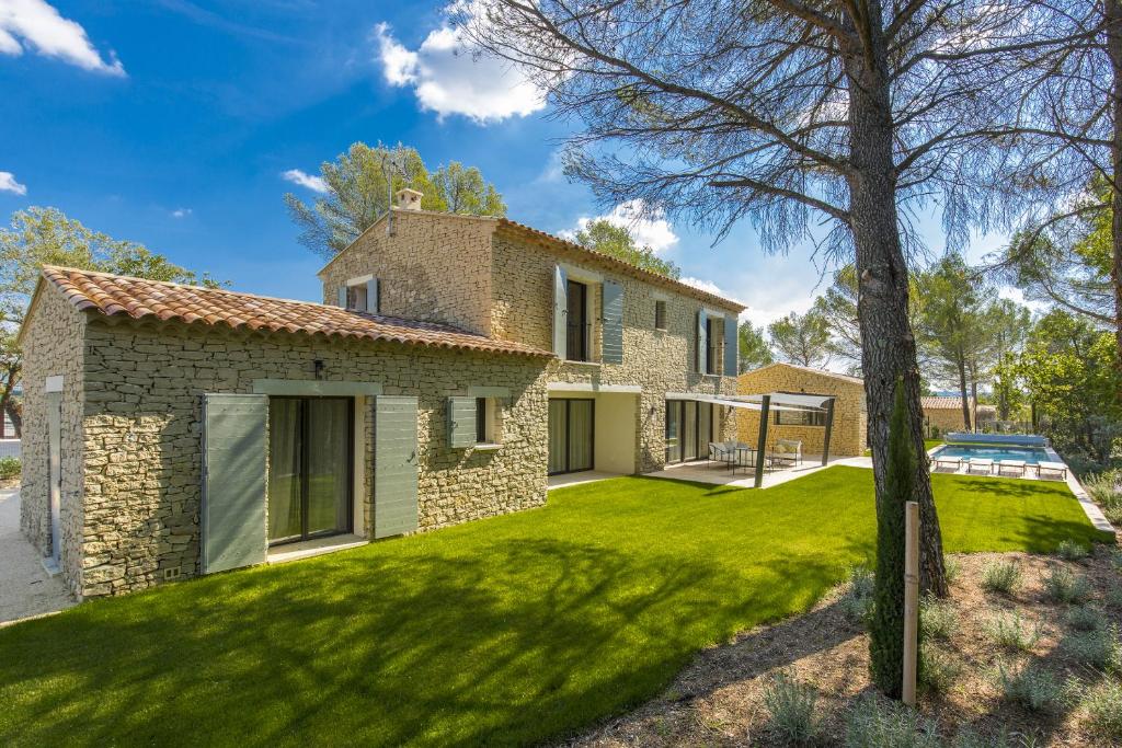 a stone house with a green yard at L'Instant Luberon in Gordes