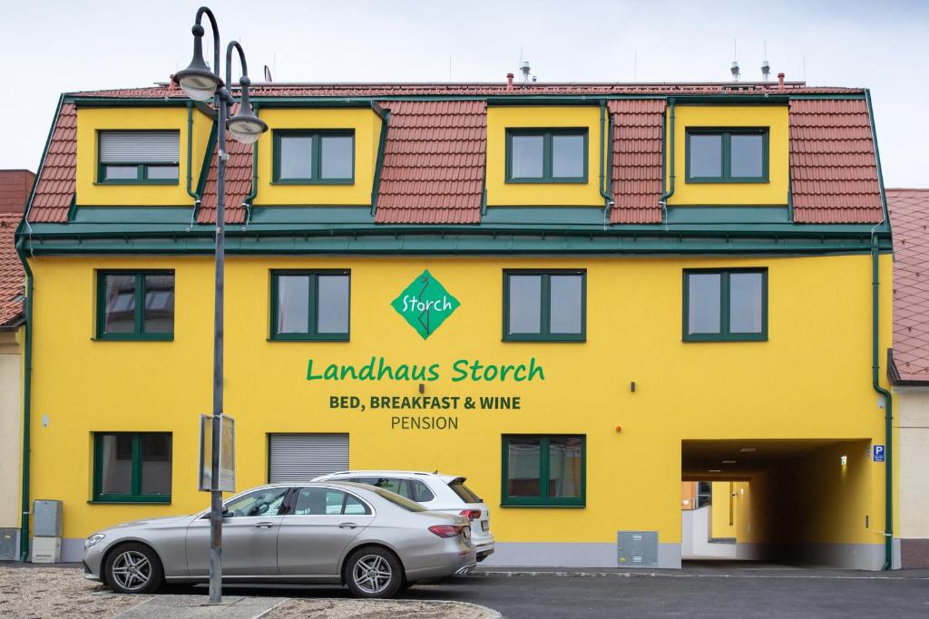 een geel gebouw met een auto ervoor geparkeerd bij Landhaus Storch - Pension in Gänserndorf