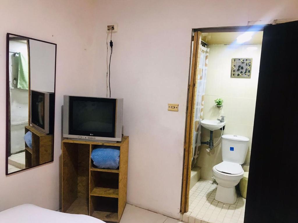 a bathroom with a toilet and a television on a shelf at hostal la 18 in Pereira