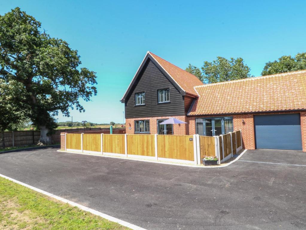 a house with a wooden fence and a driveway at Oak Tree House, 1 Homestead Gardens in Filby