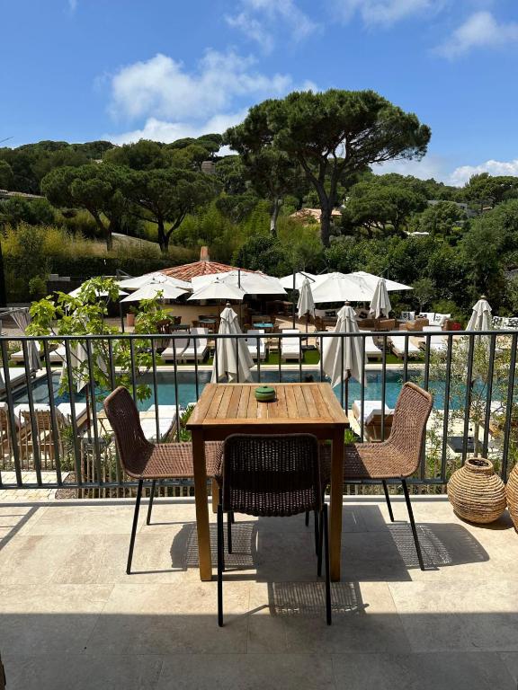 a table with chairs and umbrellas next to a pool at Hôtel L'Escalet in Ramatuelle