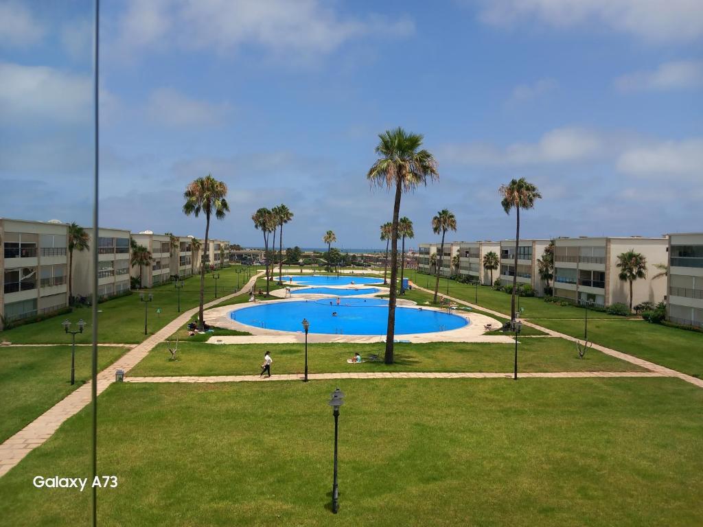 una gran piscina con palmeras en un parque en Ola Blanca en Dar Hamida