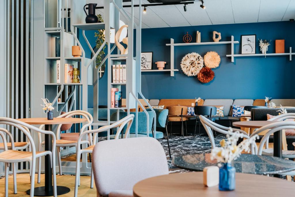 un restaurante con paredes azules, mesas y sillas en Mercure Brest Centre Port, en Brest