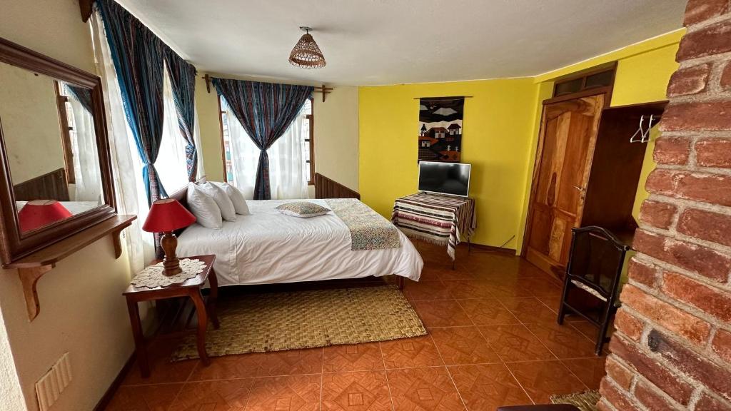 a bedroom with a bed with yellow walls and a television at Hotel Donde Ivan in Baños