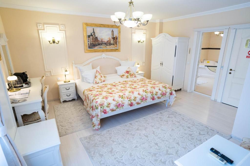 a white bedroom with a bed and a chandelier at Villa Alice in Suceava