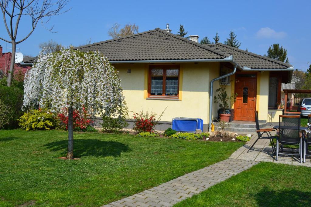 a small house with a flowering tree in the yard at Holiday Vendégház in Siófok