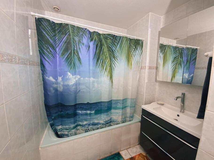 a bathroom with a window with a palm tree shower curtain at La Violette ONLY WOMEN femmes uniquement in Vénissieux