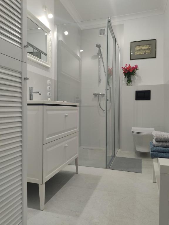 uma casa de banho branca com um chuveiro e um lavatório. em Apartament przy Wieży em Toruń