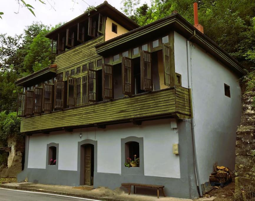 un edificio con ventanas de madera y un banco frente a él en La Naranxa, en Bárzana