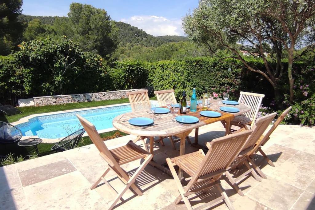 une table en bois avec quatre chaises et une piscine dans l'établissement Maison familiale avec piscine 7 personnes, à Cassis