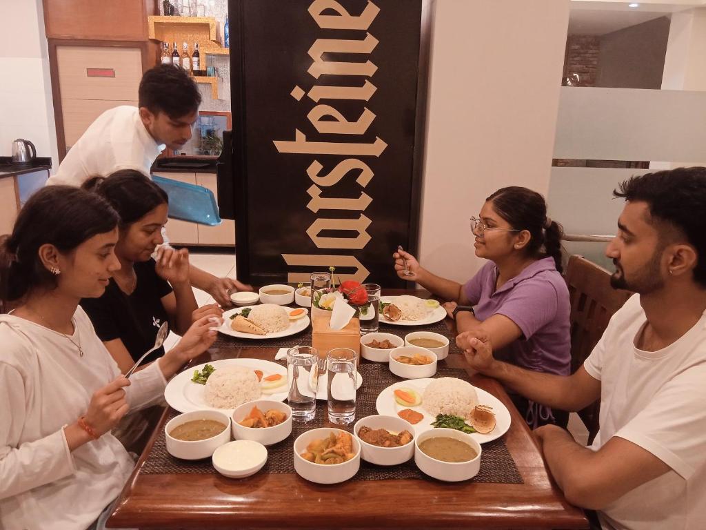 un grupo de personas sentadas alrededor de una mesa comiendo comida en Hotel Krishna Kathmandu, en Katmandú