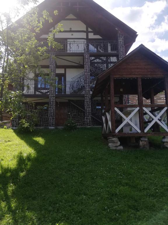 a large house with a porch and a grass yard at Садиба АнноМарі - відпочинок в Карпатах котедж Яремче in Yaremche
