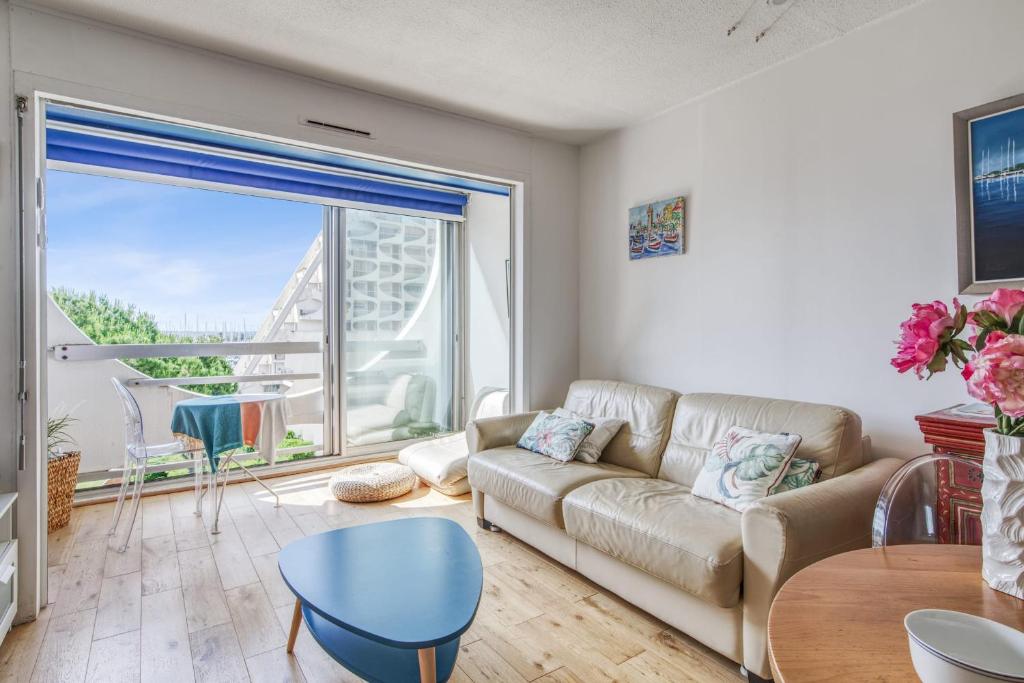 un salon avec un canapé et une grande fenêtre dans l'établissement Appartement Fages climatisé - Welkeys, à La Grande Motte