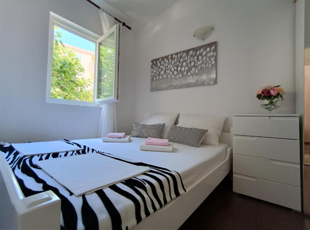 a white bedroom with two beds and a window at Apartments Vuleta in Pag