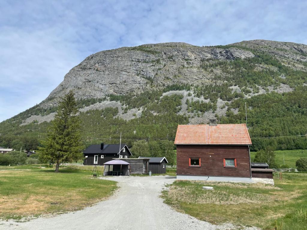 uma casa numa estrada de terra em frente a uma montanha em Old vacation house em Skjåk