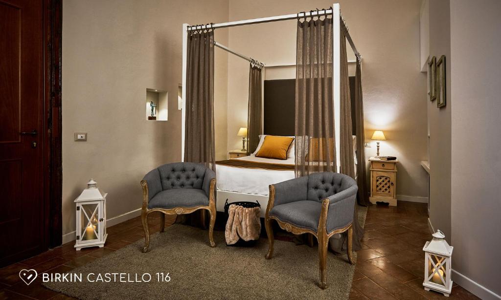 a bedroom with a bed and two chairs and a mirror at Albergo Diffuso Birkin Castello in Cagliari