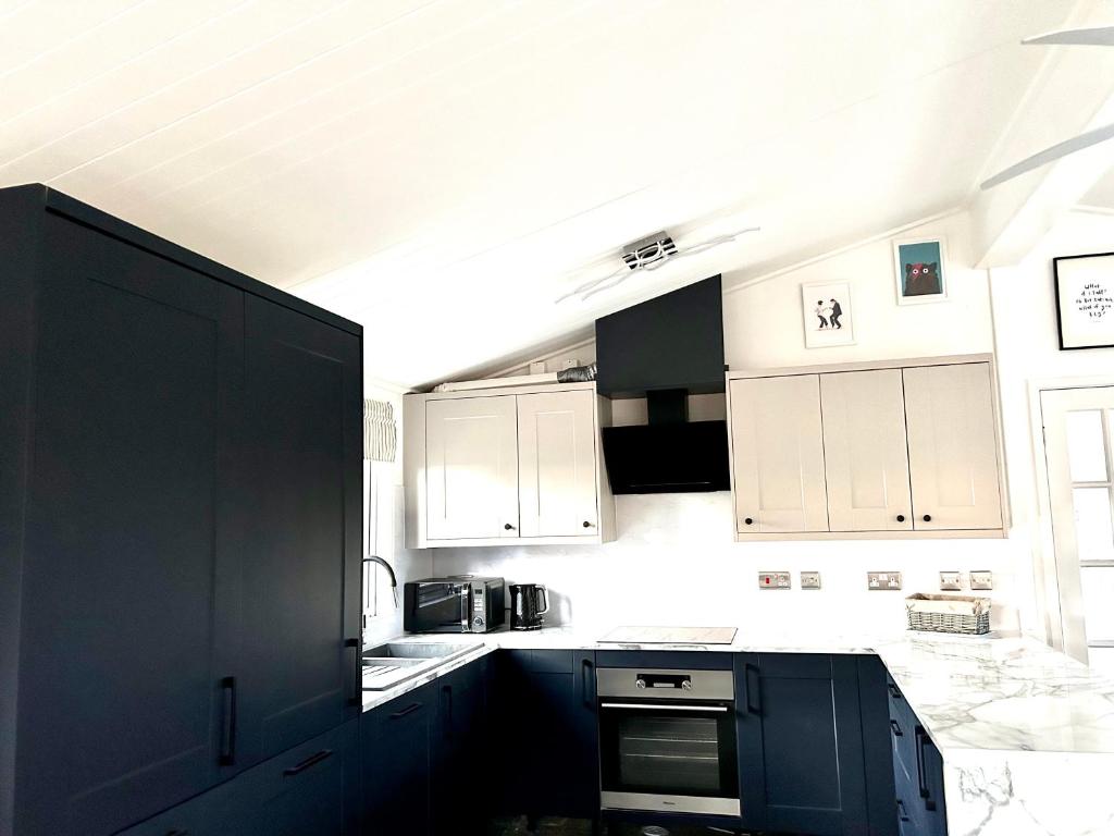 a kitchen with black and white cabinets and appliances at Woodpecker Lodge in Newquay