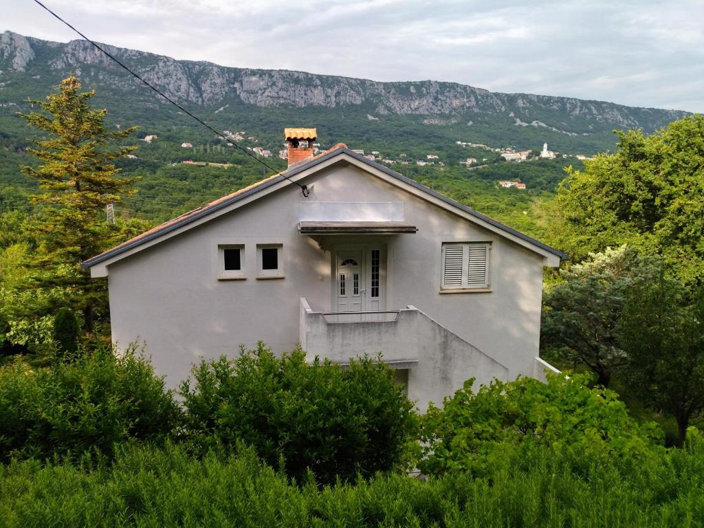 ein weißes Haus auf einem Hügel mit Bergen im Hintergrund in der Unterkunft Apartment Sana in Bribir