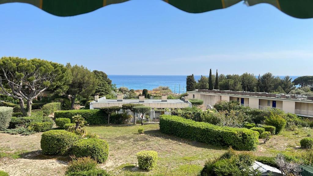 een uitzicht op een tuin met struiken en een gebouw bij Baie des Anges in La Ciotat