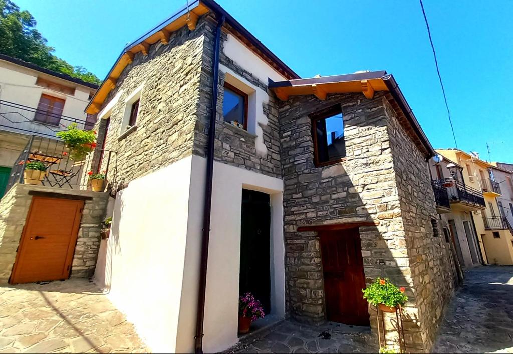 a stone house with a red door in a street at Sant'Elia B&B in Alessandria del Carretto