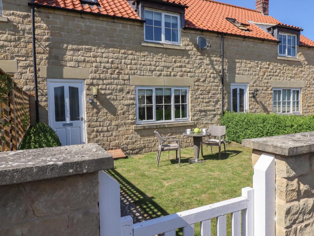 a stone house with a white fence and a table at 8 Pottergate Mews in Helmsley