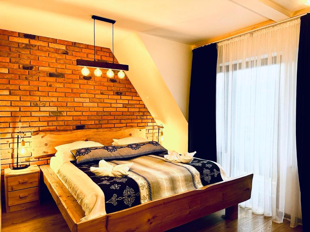 Domek Giewont في زاكوباني: غرفة نوم بسرير كبير وبجدار من الطوب