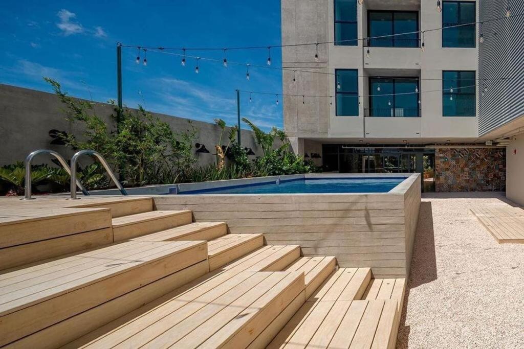 a swimming pool with wooden steps next to a building at Urbn Moras in San José
