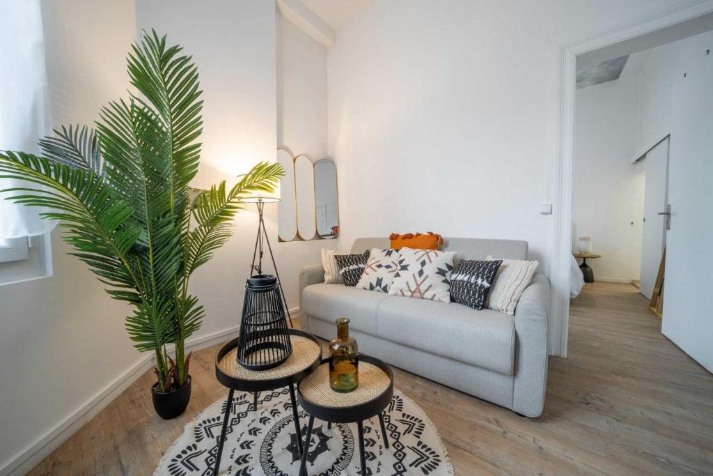 - un salon avec un canapé et un palmier dans l&#39;établissement Bright 30 m near the Place de la Comédie, à Montpellier