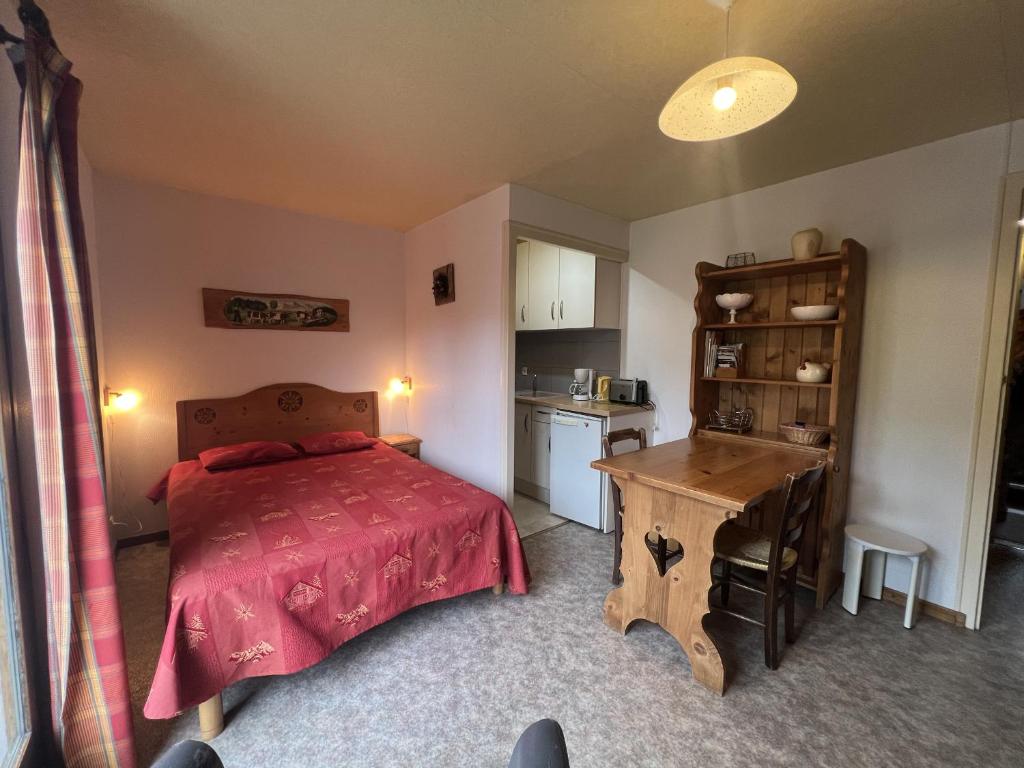 une chambre avec un lit et une table et une cuisine dans l'établissement Gemeaux S, studio proche pistes de ski et village, à La Clusaz