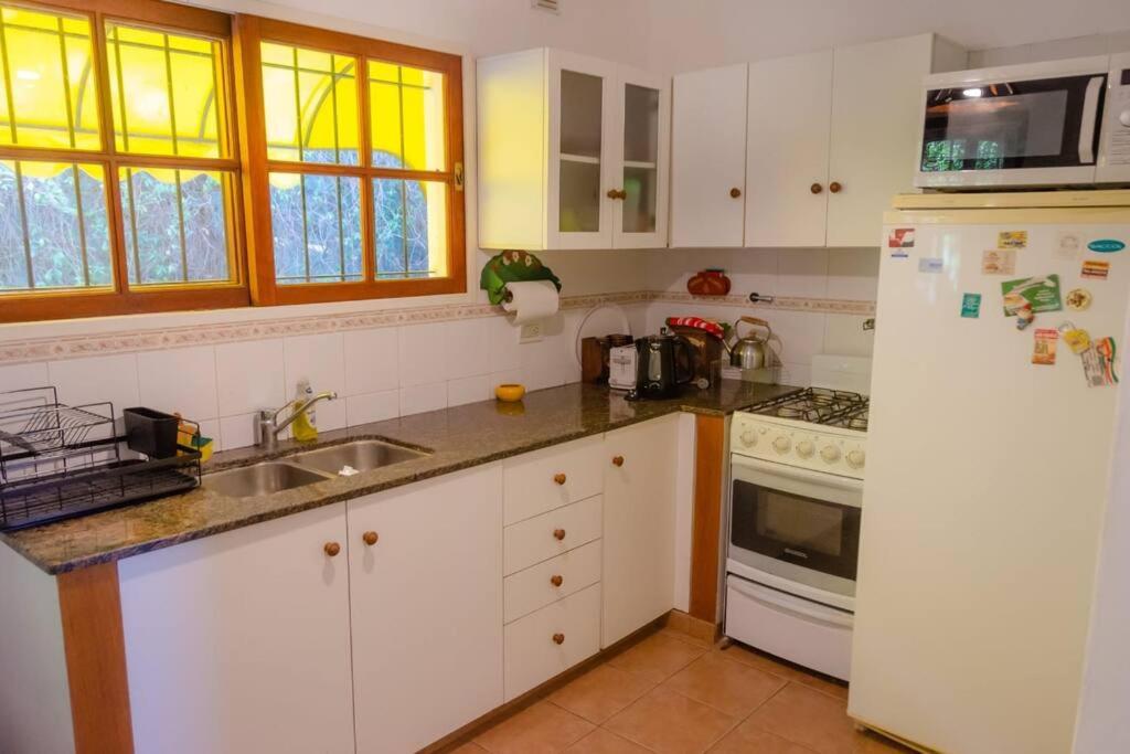 cocina con armarios blancos y refrigerador blanca en Unser traum en Villa General Belgrano