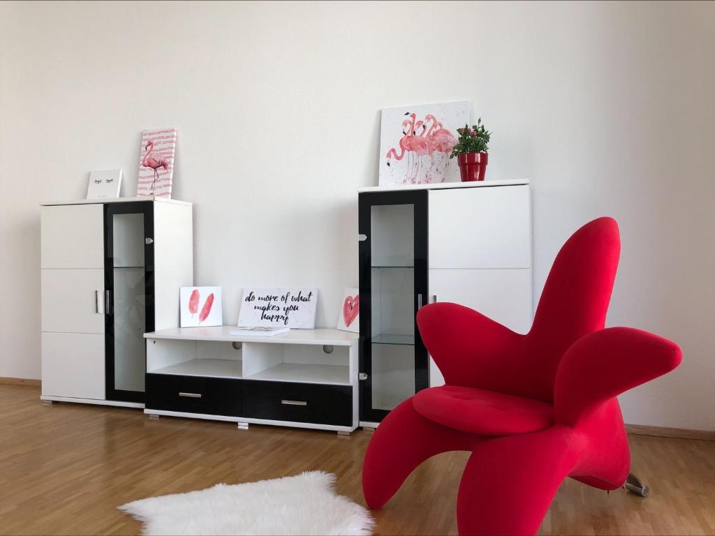 uma cadeira vermelha num quarto com uma parede branca em Moderne Alpenblick Apartment em Friedrichshafen