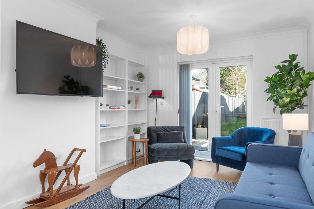 uma sala de estar com cadeiras azuis e uma televisão em Brett Stays - Lower King Weston House em Avonmouth