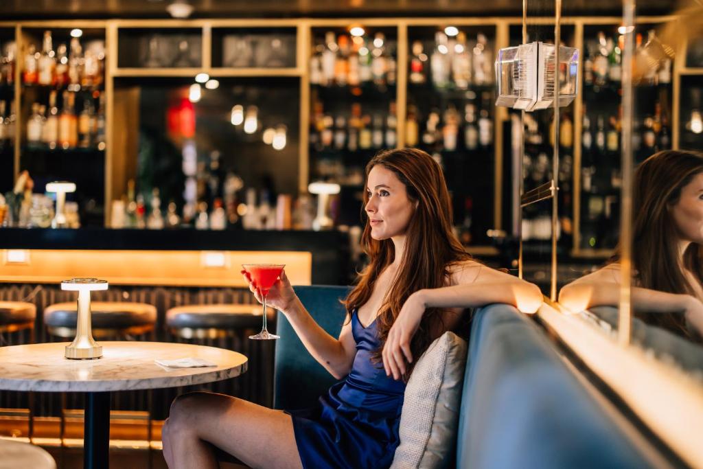 Eine Frau, die in einer Bar sitzt und einen Drink hält. in der Unterkunft Hotel Indigo NYC Downtown - Wall Street, an IHG Hotel in New York