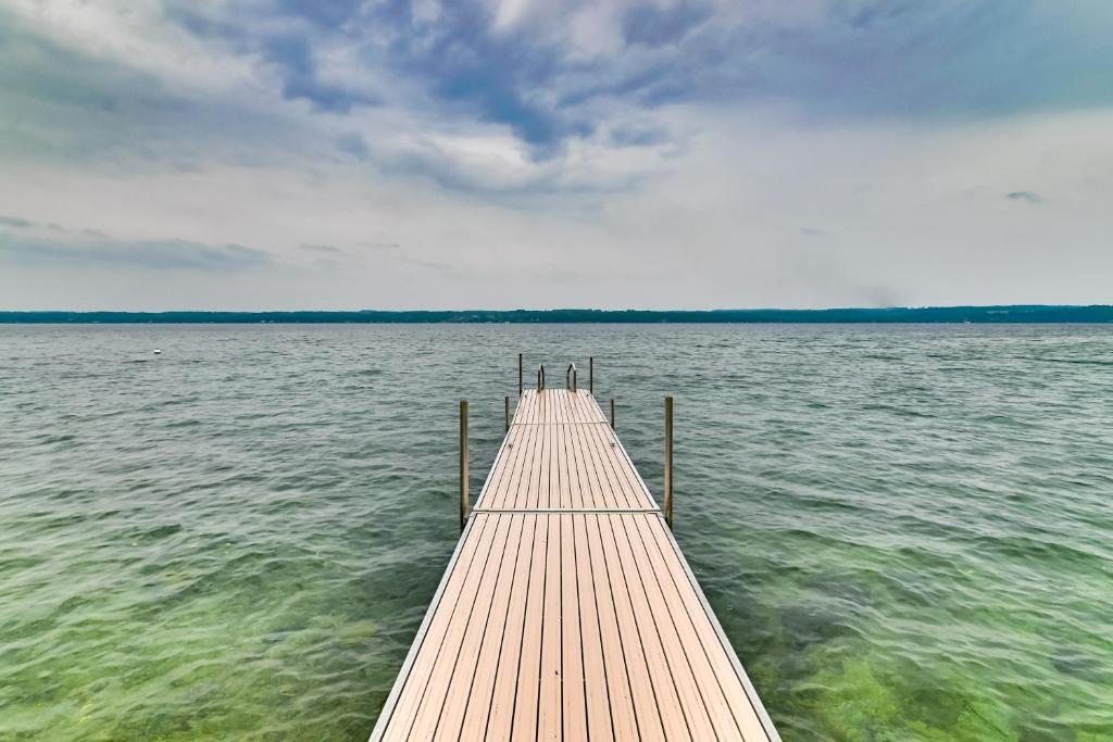 a wooden pier in the middle of a body of water at Spacious Canandaigua Lake House with Dock and Kayak! in Canandaigua