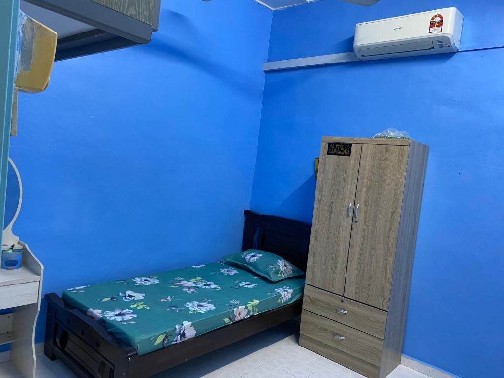 Cama pequeña en habitación con pared azul en 83 Homestay en Melaka