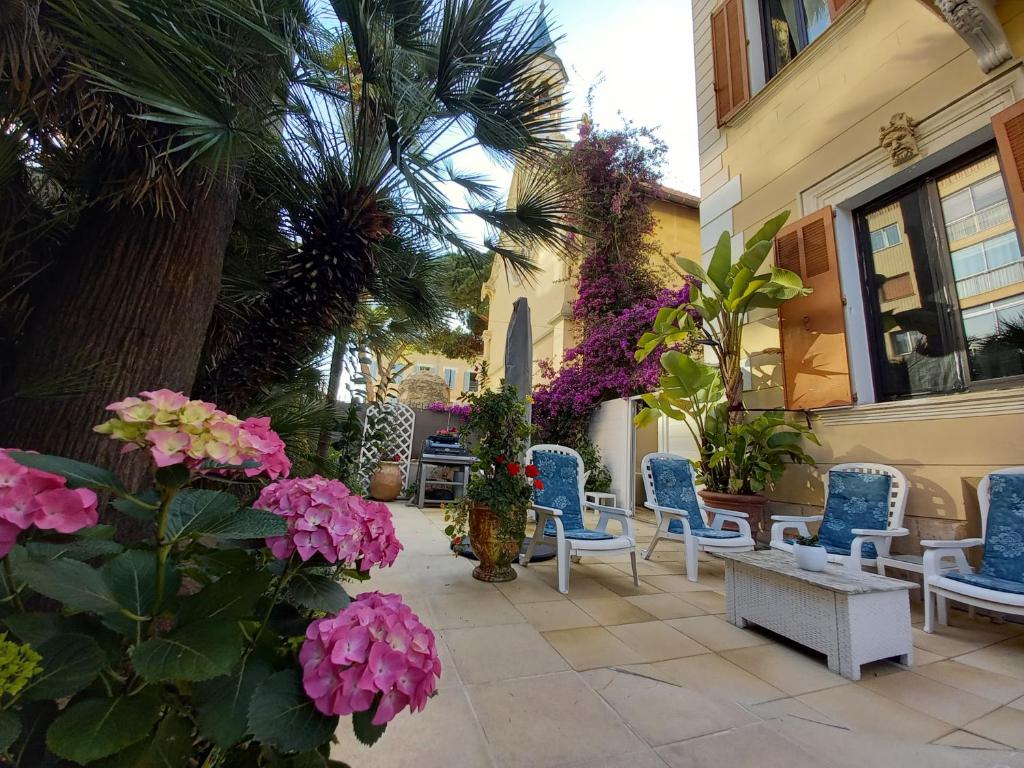 un patio avec des chaises et des fleurs et un bâtiment dans l'établissement La MASCOTTE, à Vallauris