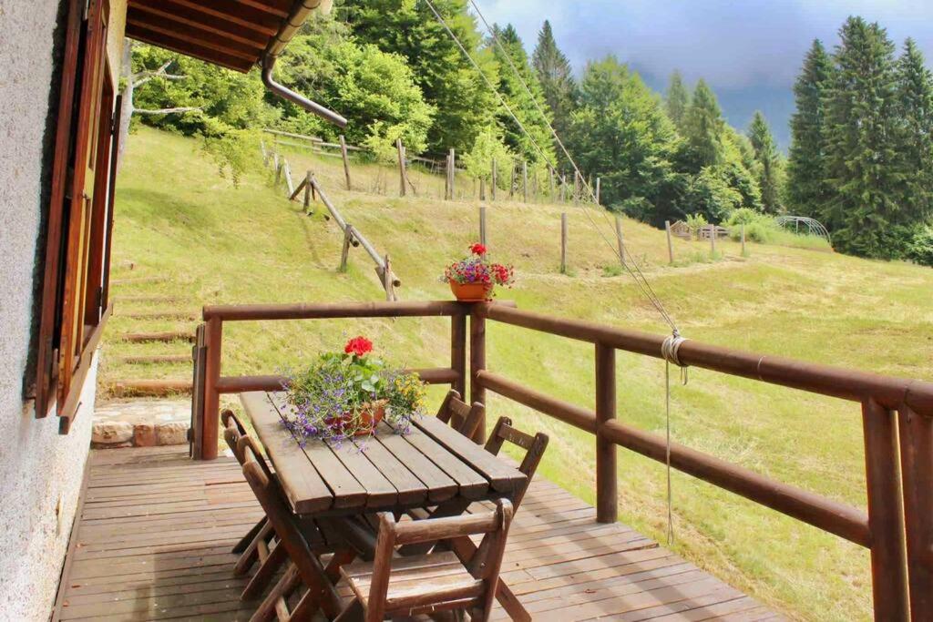 una terraza de madera con una mesa con flores. en * Chalet inside the nature* [12 guests + WI-FI], en Siror