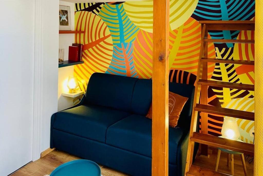 - un salon avec un canapé bleu et un mur coloré dans l'établissement Studio à 800m de la Cathédrale, à Reims