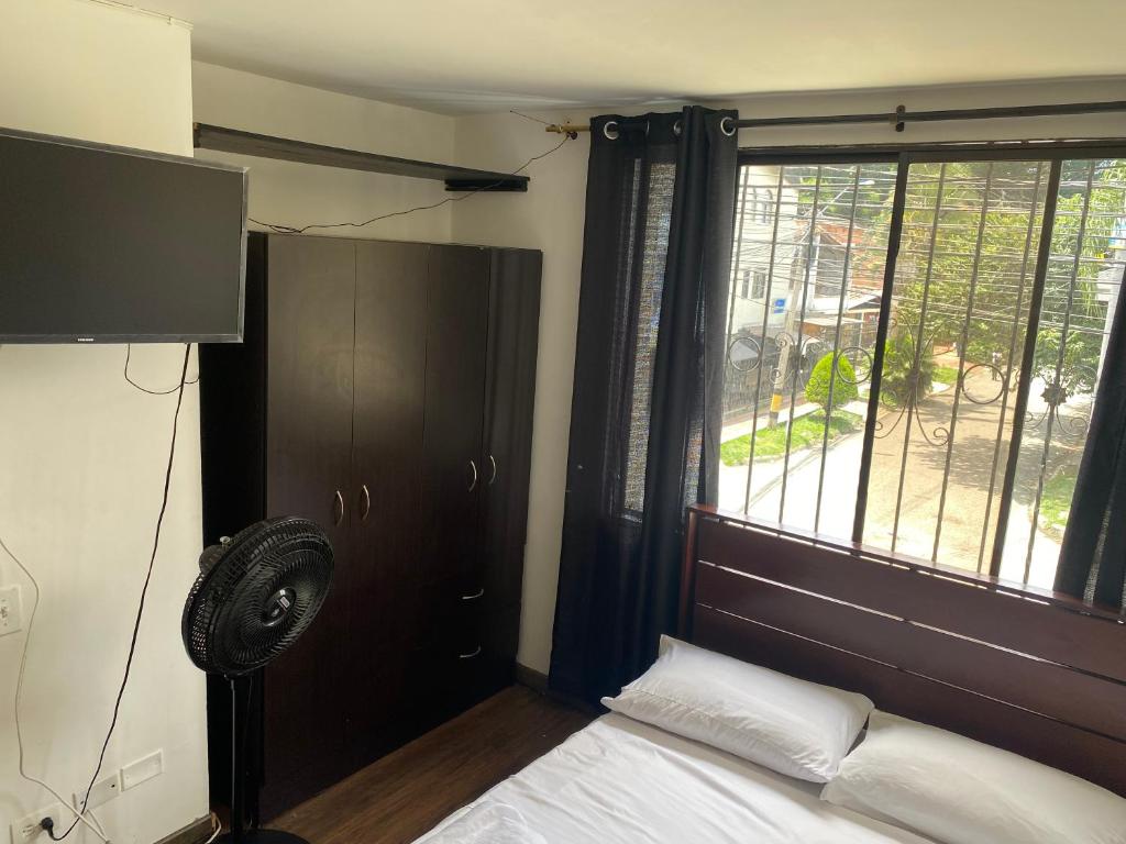 a bedroom with a bed with a fan and a window at Apartamento laureles Estadio Medellín 203 balcon in Medellín