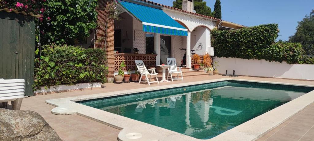 een zwembad met een tafel en stoelen naast een huis bij Chalet Sol y Sombra in Pals