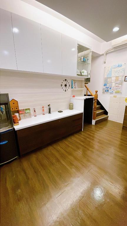 a kitchen with white cabinets and a wooden floor at Sun B&amp;B in Taitung City