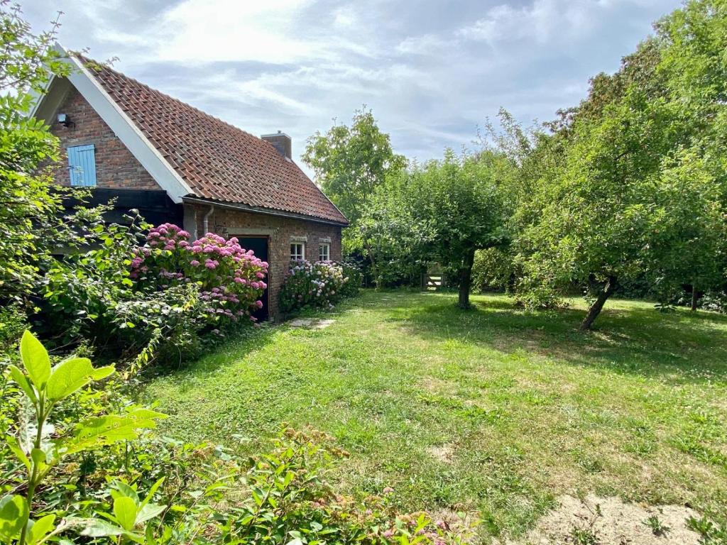 una casa de ladrillo con un patio con árboles y arbustos en Holiday home Vossennest en Veere